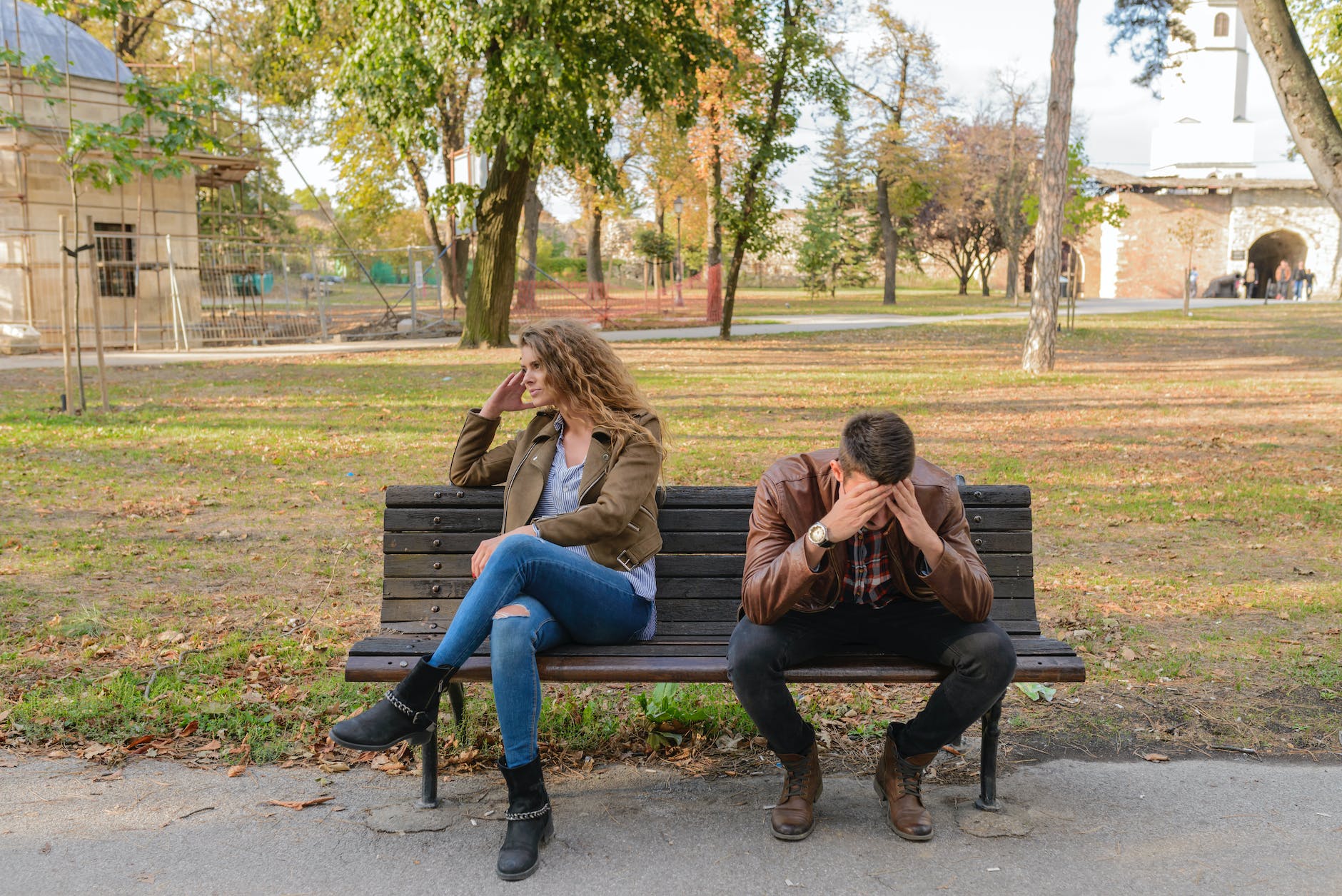 woman and man sitting on brown wooden bench feeling stress.