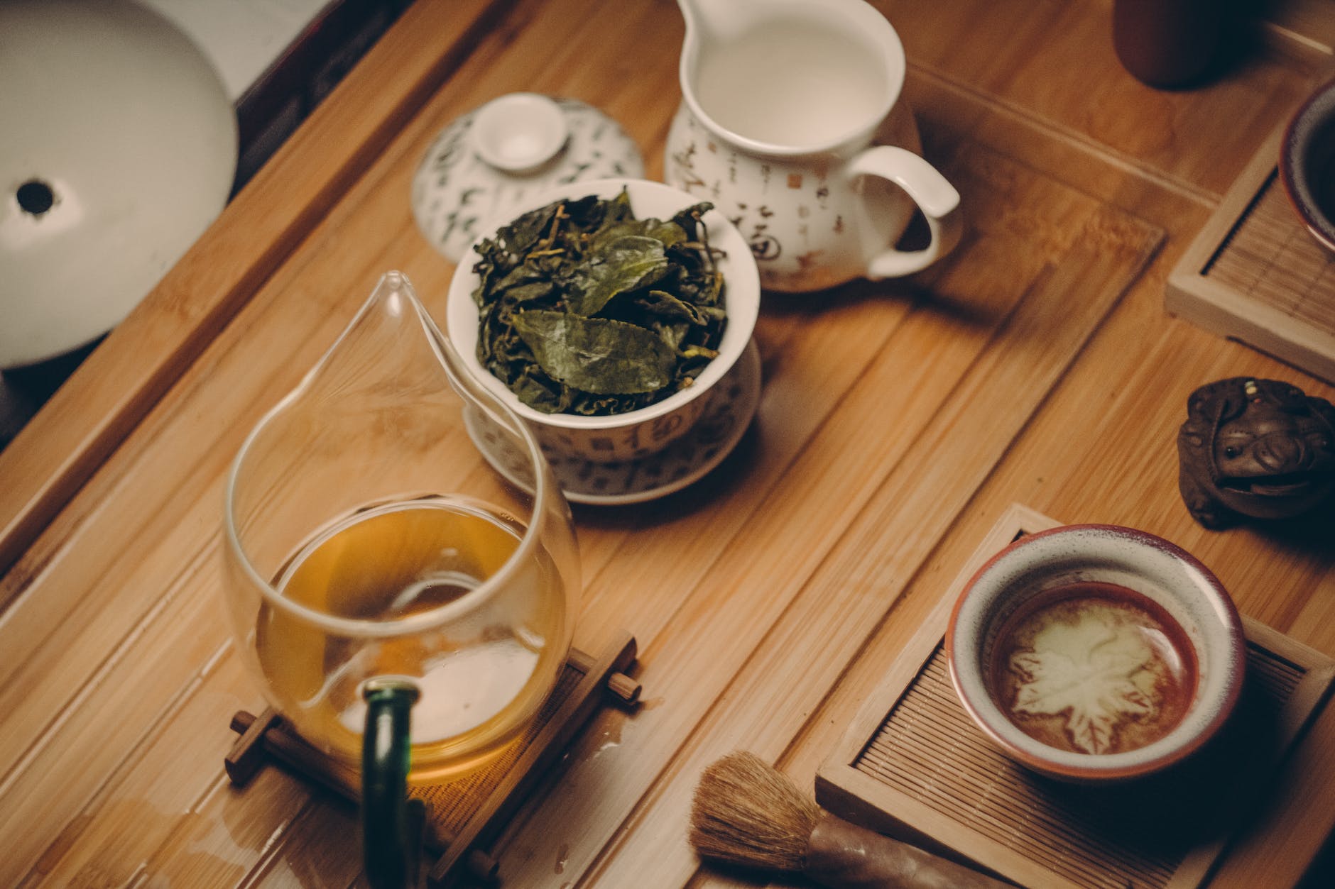 Green tea: white ceramic teapot beside cup with leaves