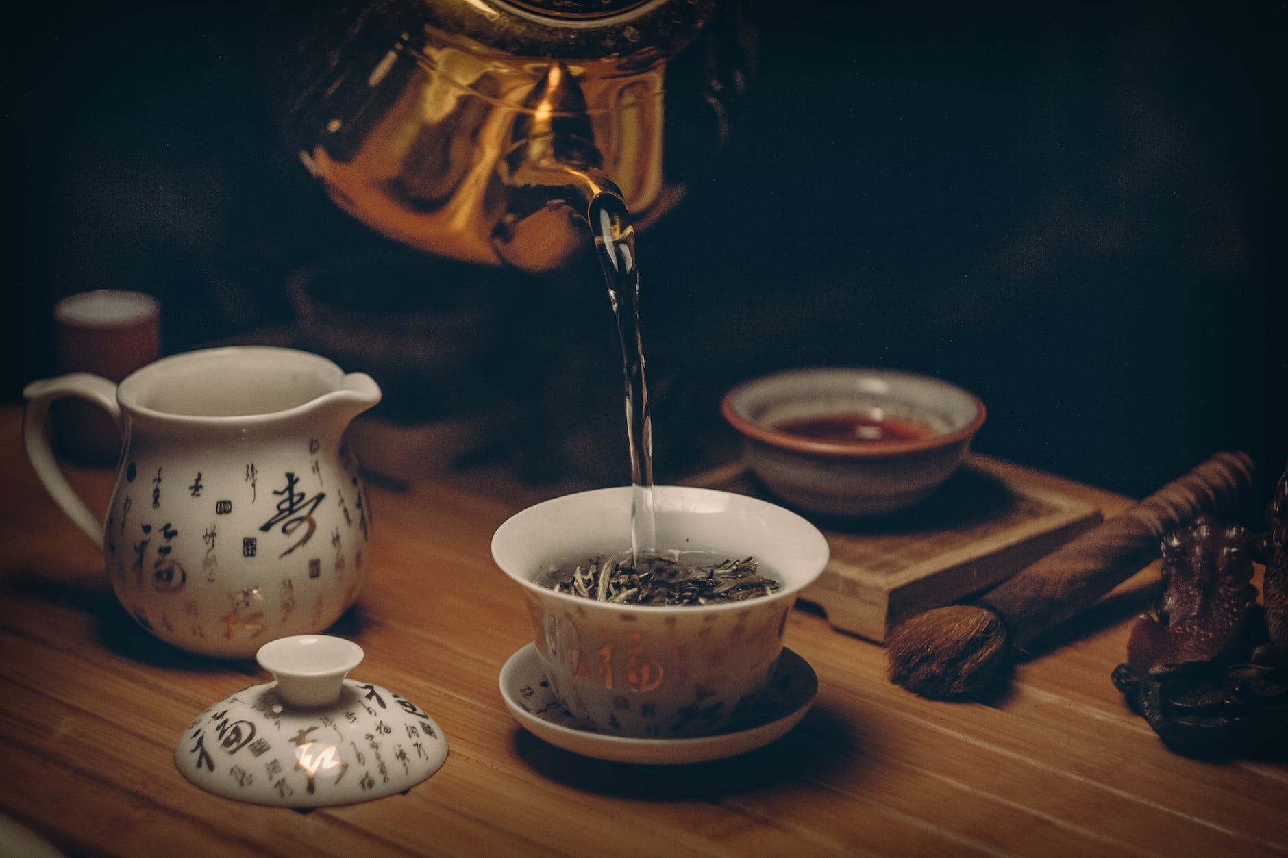 green tea :gold kettle pouring hot water on cup of tea