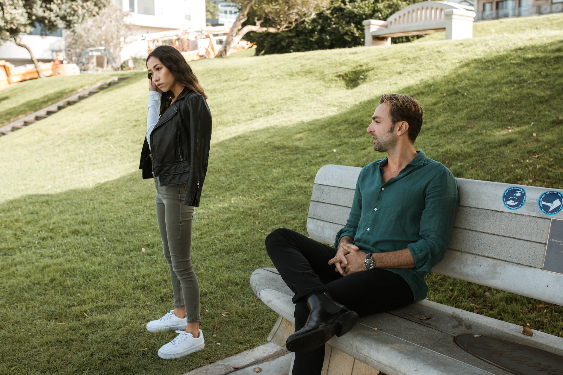 a man sitting on a bench while talking to a woman