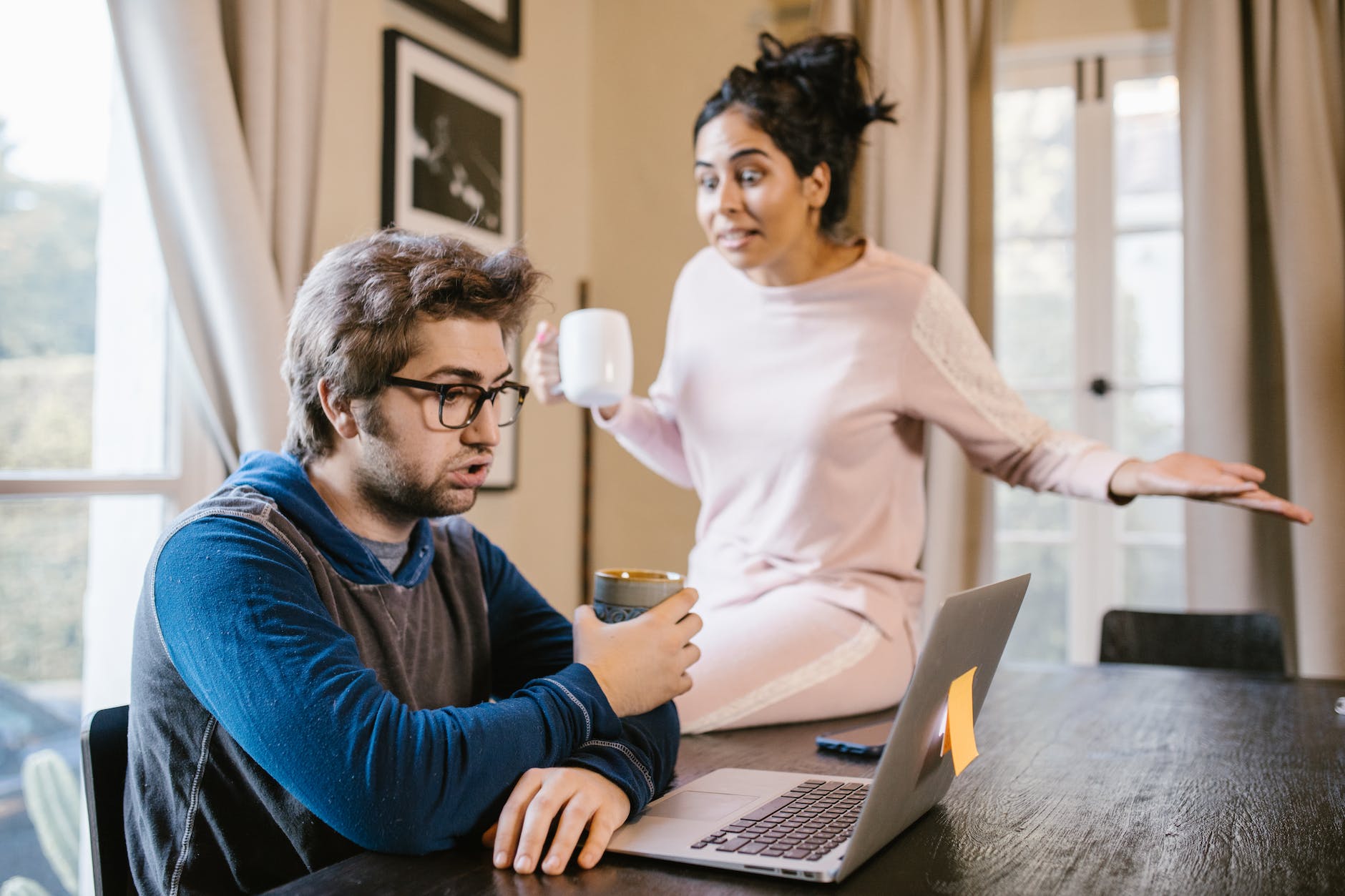 a man sitting in front of a laptop beside an upset woman