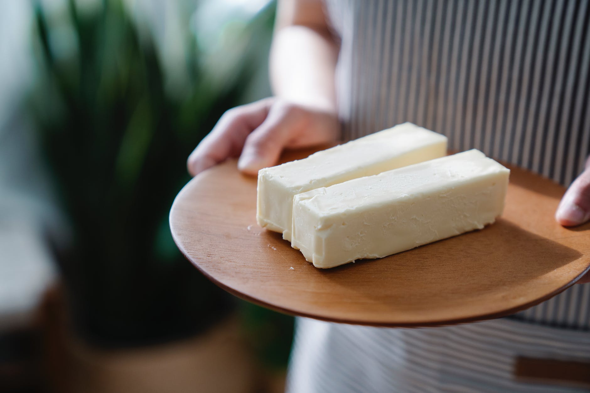 close up shot of a person holding a wooden plate with sliced butters: healthy fats implications