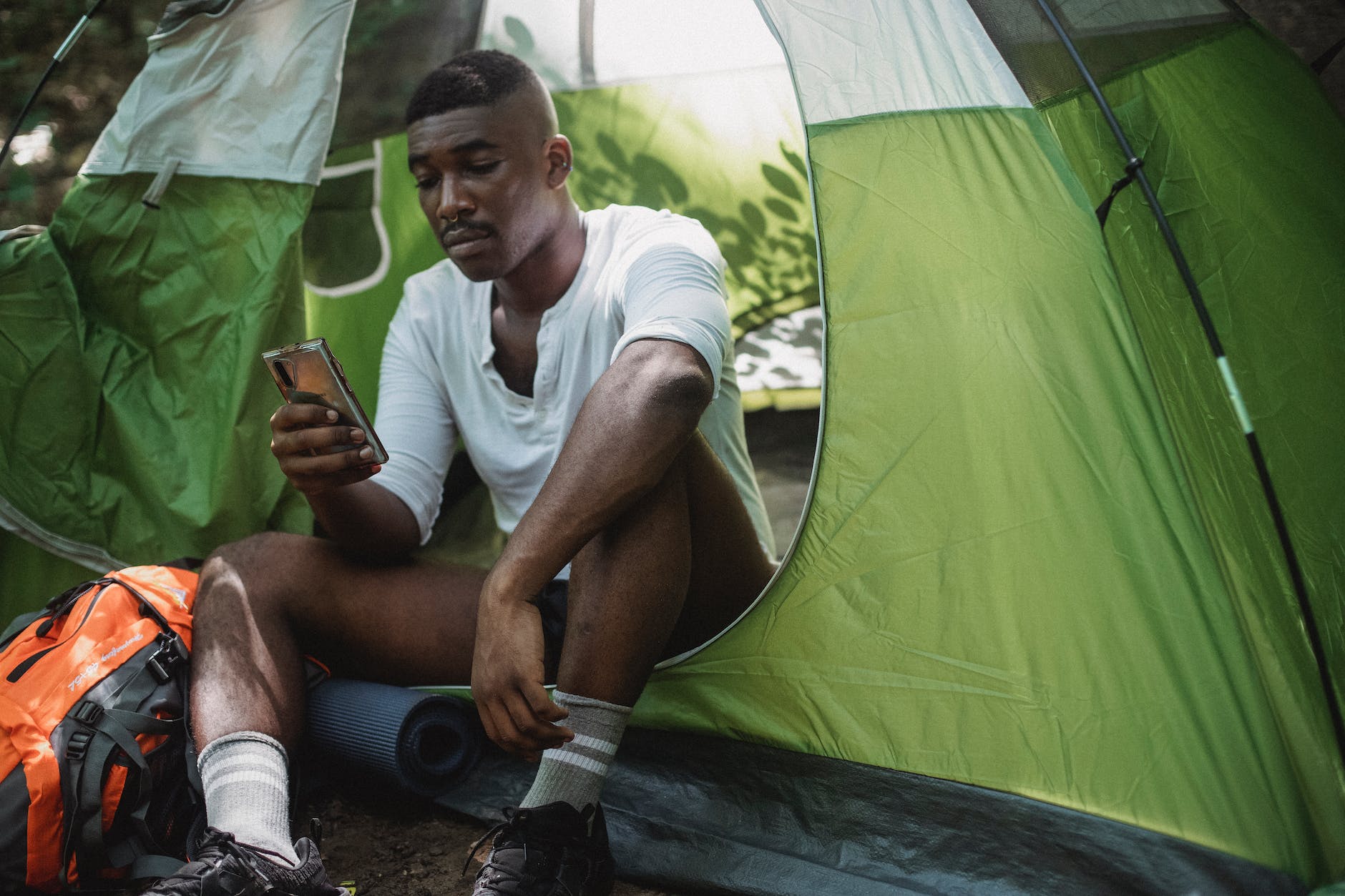 unhappy black man surfing smartphone in tent, signs a man is unhappy in his relationship