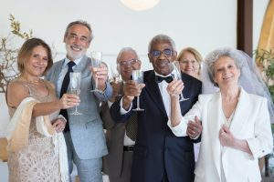 elderly people holding wine glasses while smiling at the camera