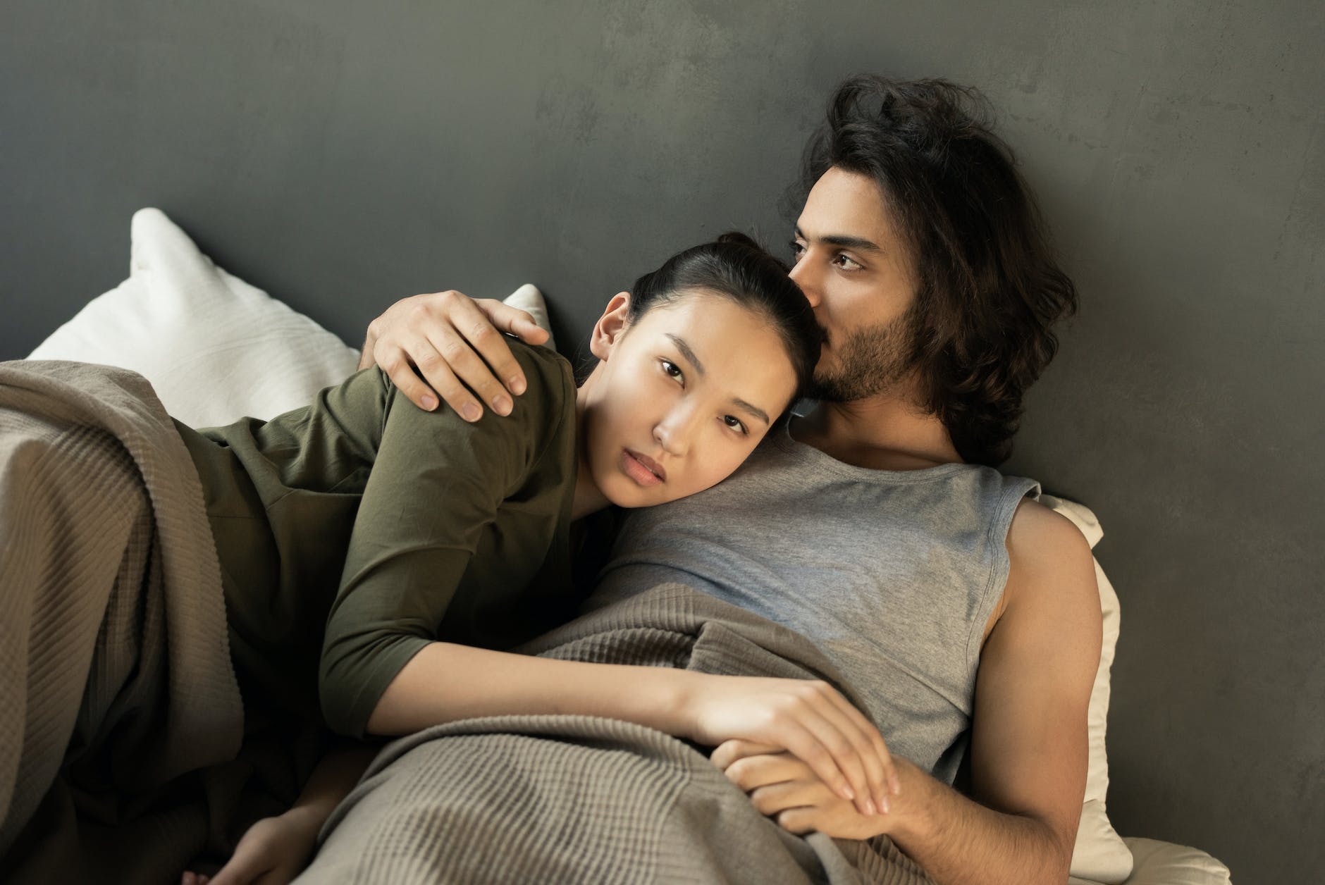 woman in green top lying on a man s chest in bed