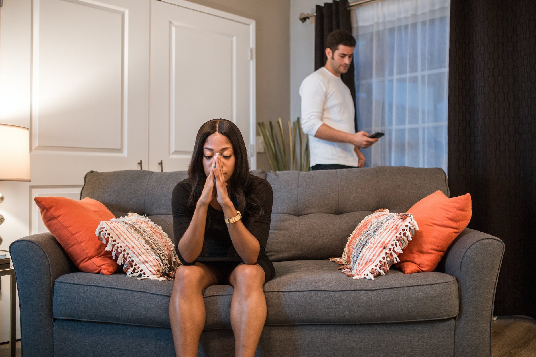 a woman sitting on the sofa while a man is standing at the back