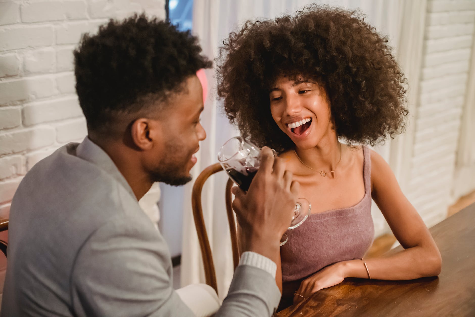 smiling black couple drinking wine while having date at table