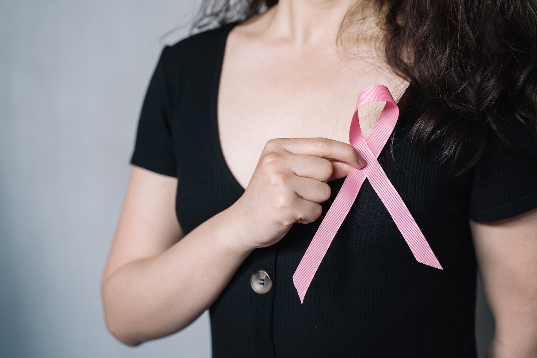 woman holding pink ribbon for breast cancer