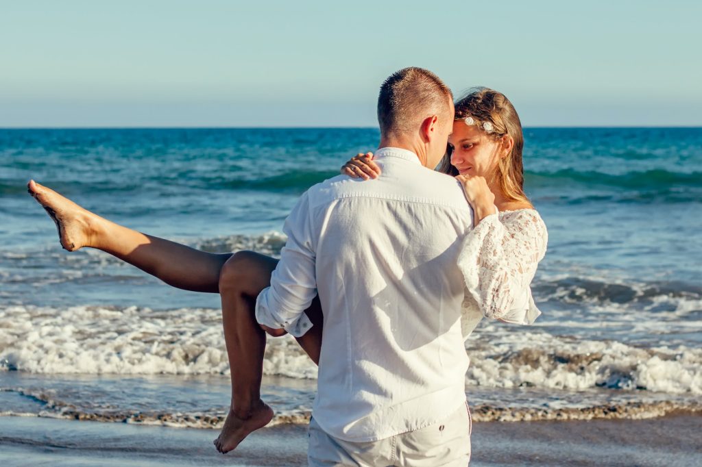 man carrying woman beside shoreline