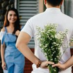 Man Holding Baby's-breath Flower in Front of Woman Standing Near Marble Wall