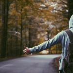 person standing beside road doing handsign